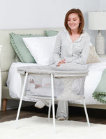 Smiling at baby resting in the Baby Basics™ Infant Bassinet